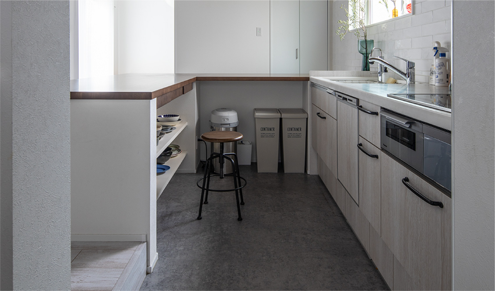 一段下がったキッチンの床は質感を変えた。カウンター下にゴミ箱や収納スペースを設けてすっきり
