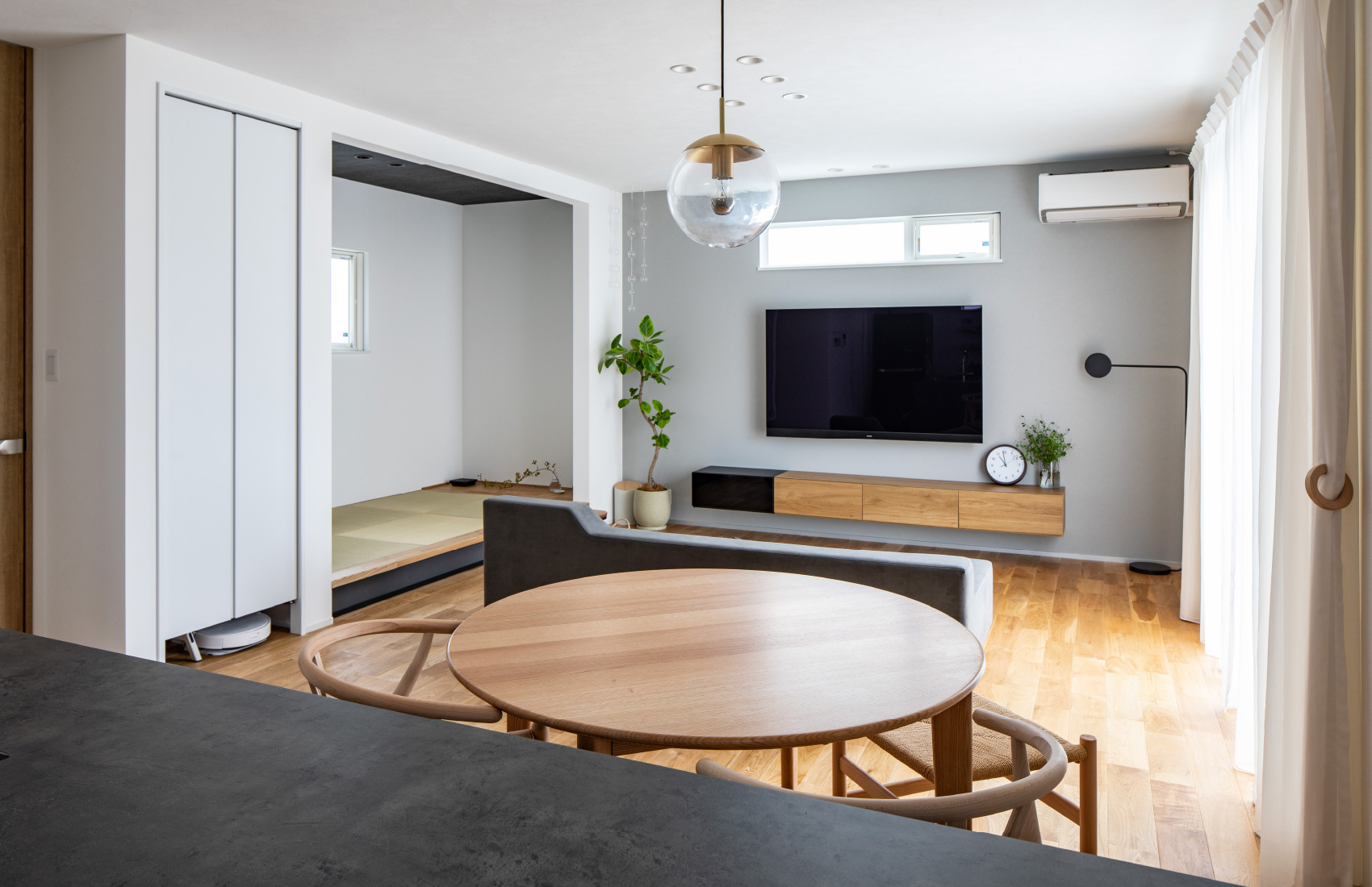 キッチンから見たリビングダイニング。すっきりとしたテレビまわりは、お気に入りのインテリアがよく映える。左の収納扉の下はロボット掃除機の収納スペース。