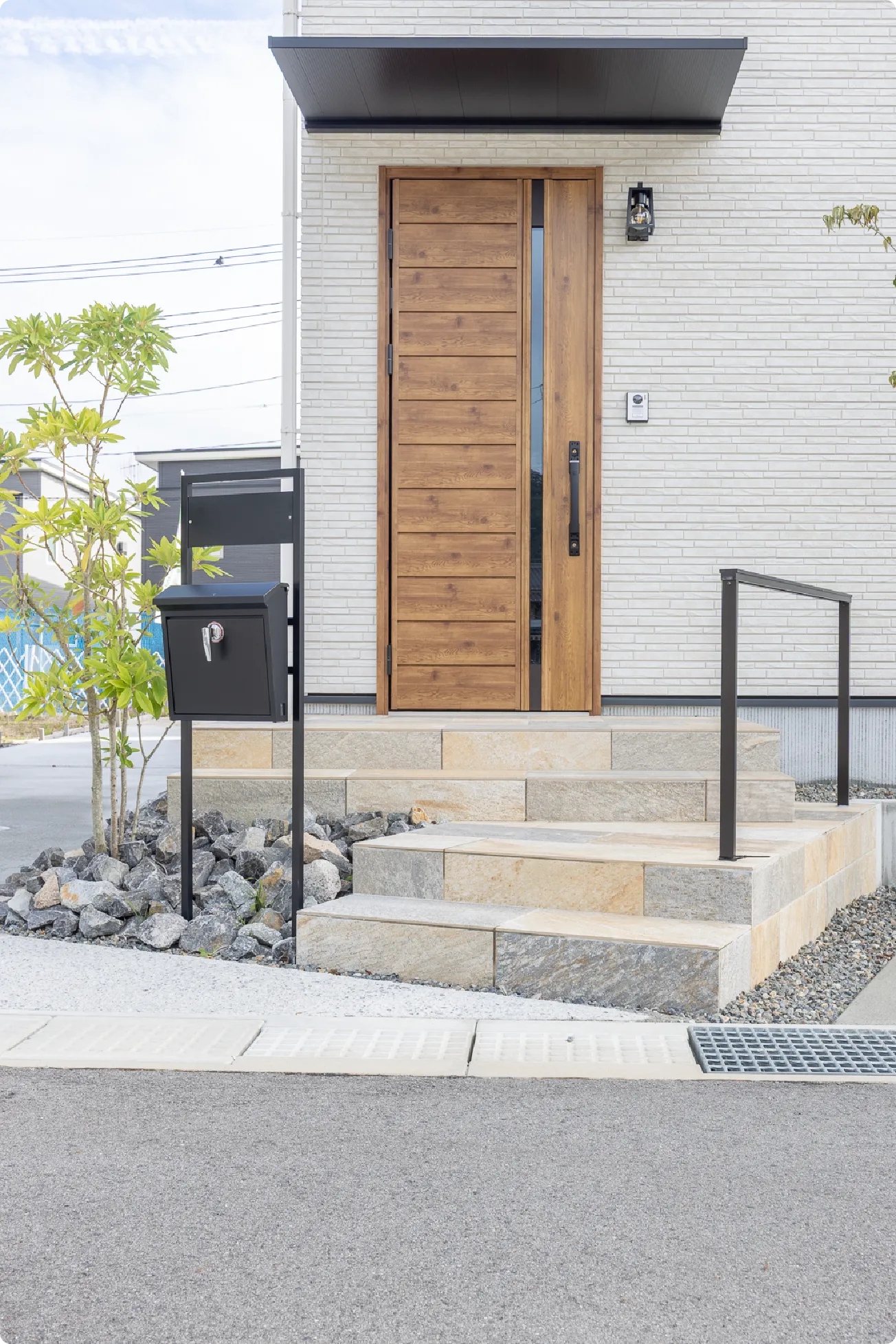 アプローチ部分は大判の大理石調のタイルで重厚感を持たせた雰囲気に。木目の玄関扉と石目のタイルが調和し、自然を感じる佇まいへと演出します。