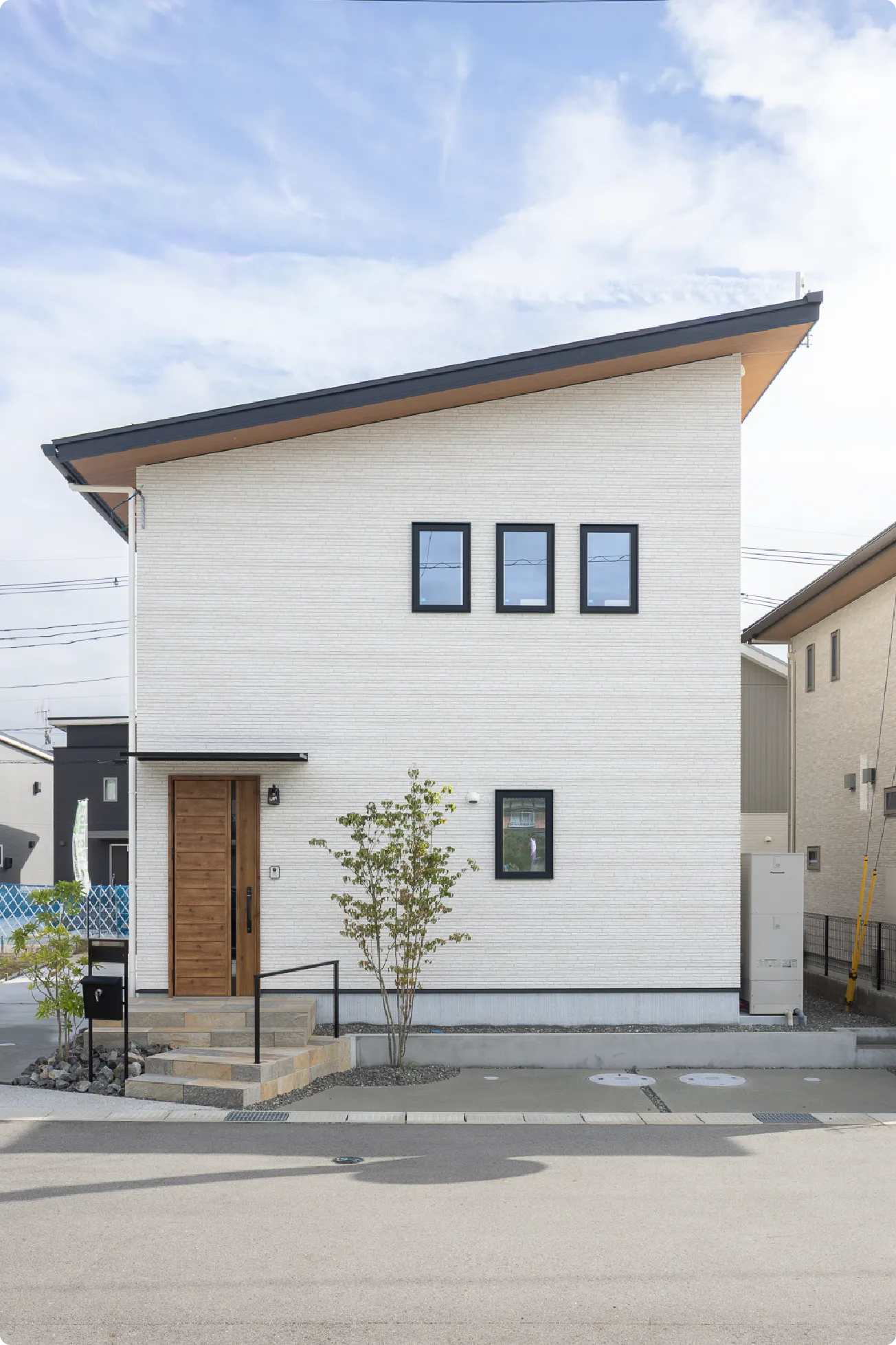 明るい色味がベースのスッキリとした外観。木目の玄関ドアや大判の玄関タイルが特徴です。