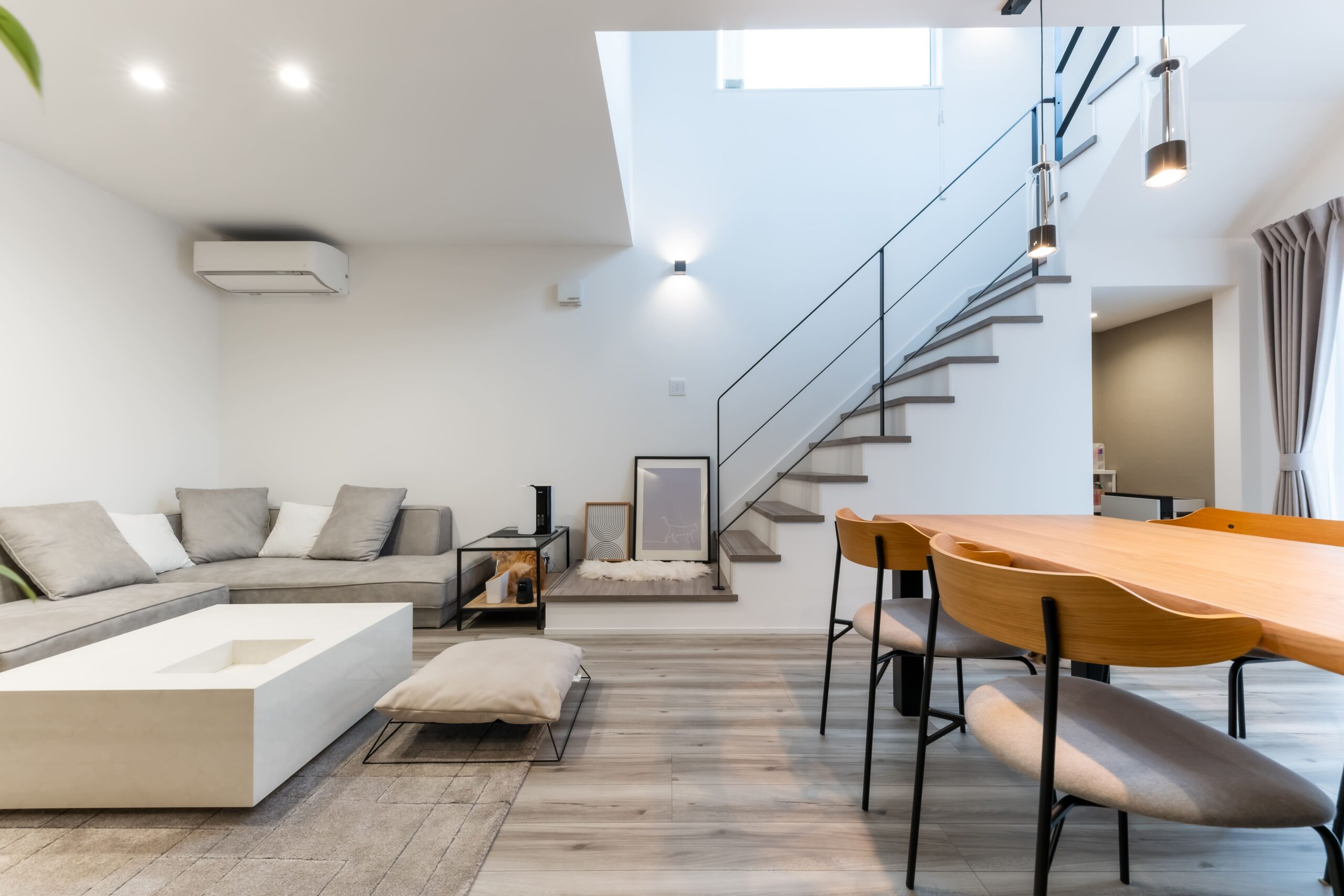 グレージュの床と白い壁でコーディネートしたモダンなリビングダイニング。白のセンターテーブルは空間に合わせたオーダー品。リビング階段はアイアンの手すりですっきりまとめた。