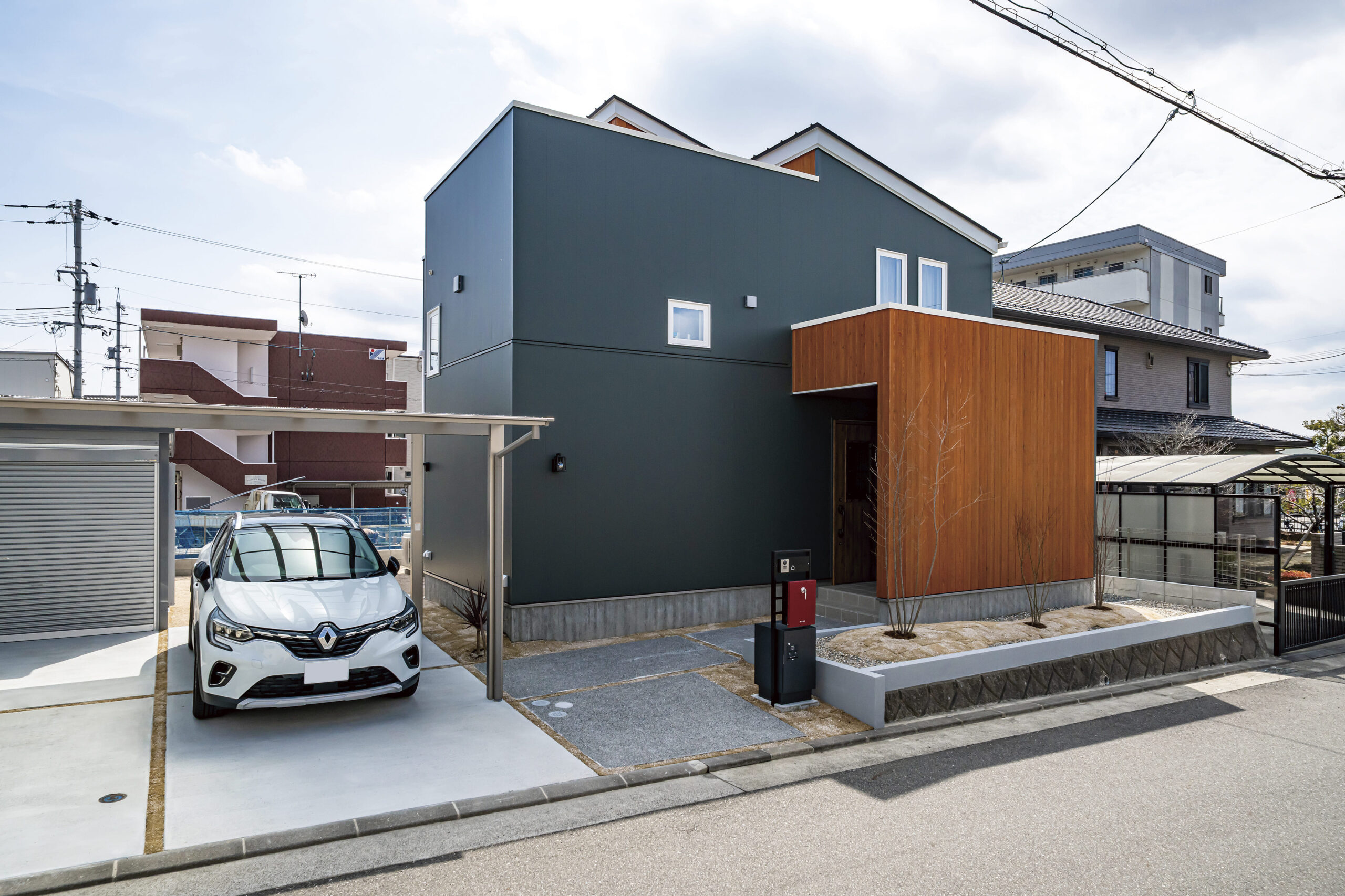 外壁の色は奥様が好きなモスグリーンをセレクト。ピニー（赤褐色）の羽目板の目隠し壁とのコントラストもおしゃれ。玄関ポーチ上部も覆われているので雨天でも濡れにくい。