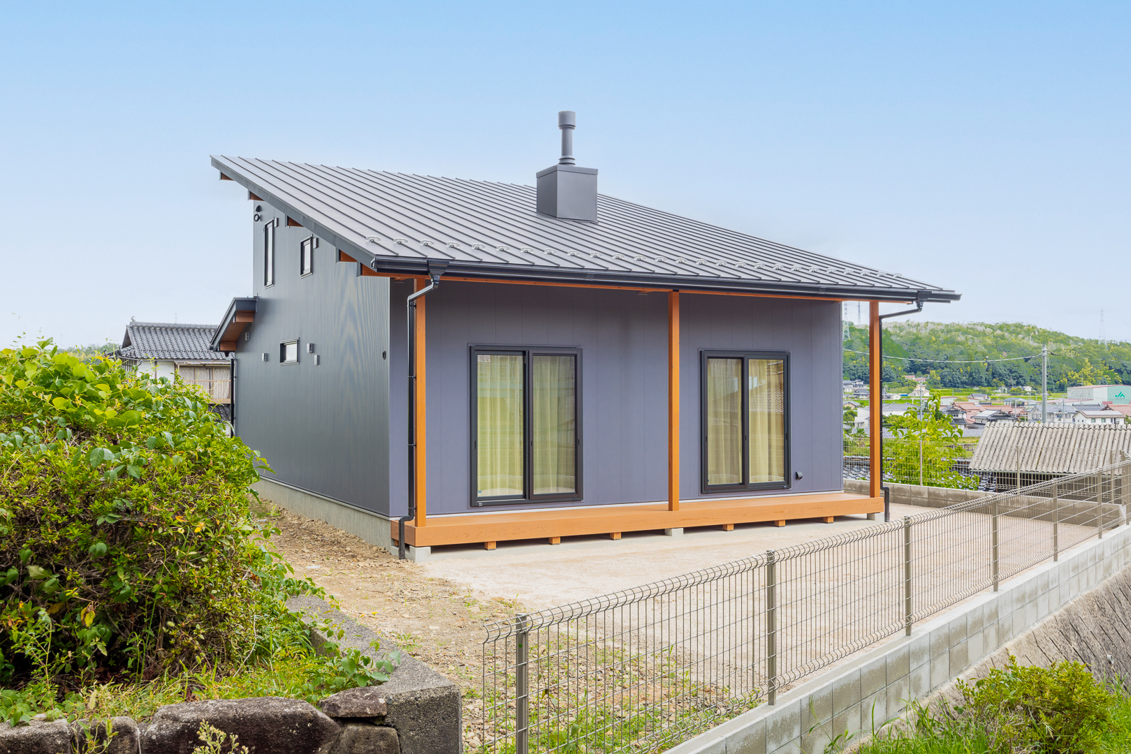 南側には大きな窓を配置し、リビングにたっぷりの光を取り込めます。薪ストーブの煙突がデザインのアクセントになっています。