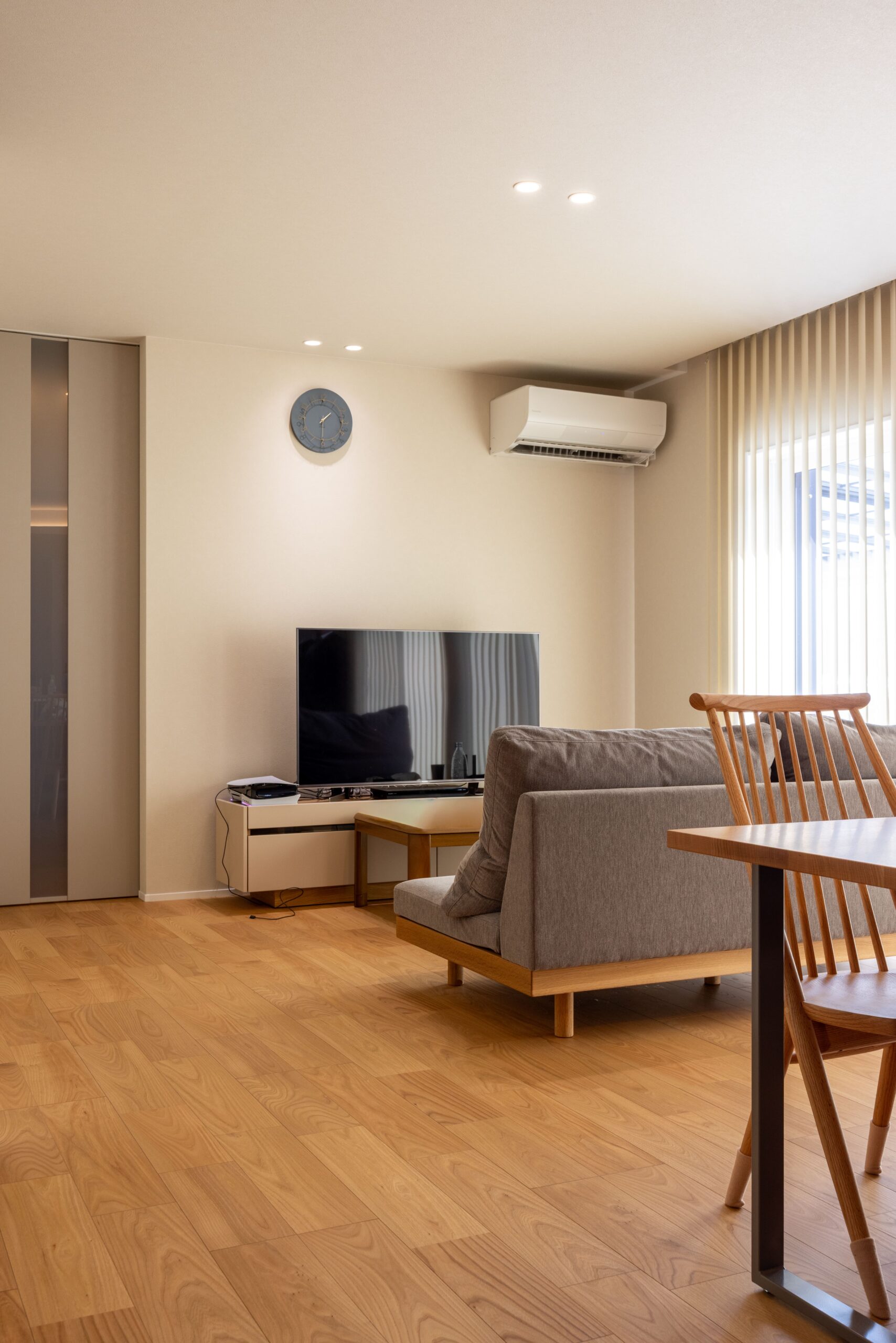 ダウンライトの下に飾ったお気に入りの時計が、暮らしのリズムを彩ります。テレビまわりにはゲーム機やグッズを置き、ご夫婦らしい“好き”を感じられる空間が広がっています。