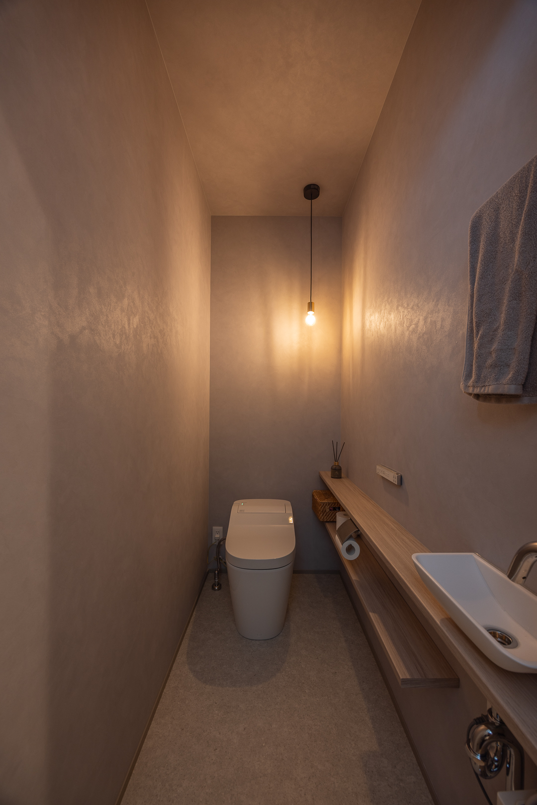 落ち着いた色味のクロスと間接照明で落ち着きのある空間に。小物を置ける棚があり実用性も兼ね備えている。