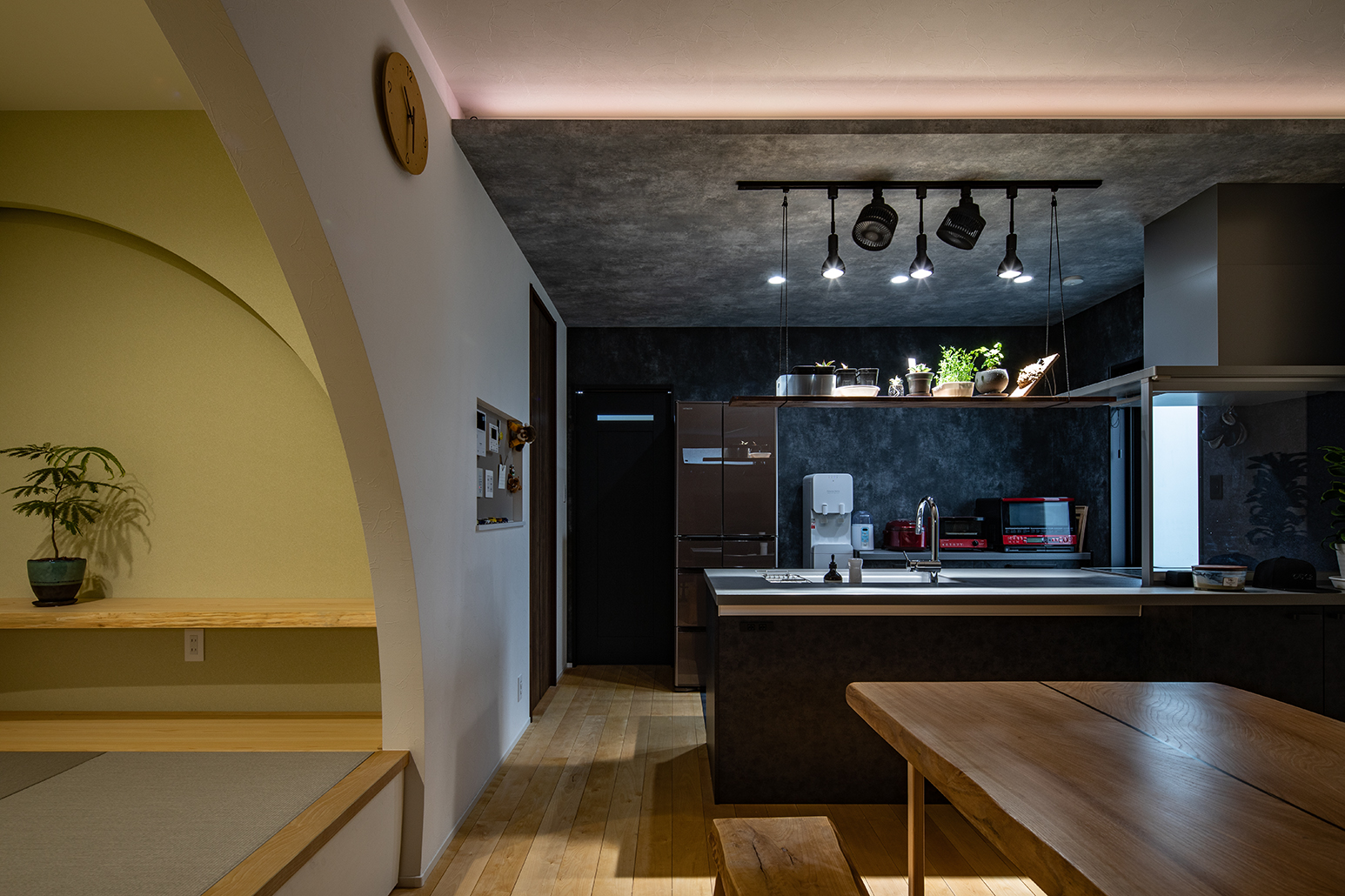 イエロー系のクロスを貼ったタタミコーナーは和モダン、下がり天井に間接照明を設けたキッチンは洋風で、２つの異なる雰囲気が上手く融合した住空間