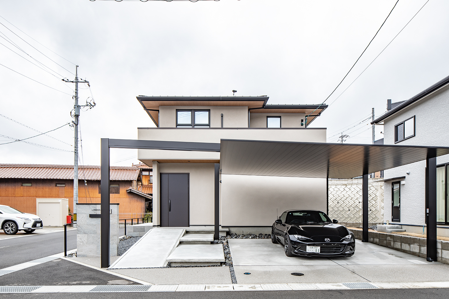 塗り壁仕上げにしたお気に入りの外観。カーポートは両側の柱の間を5.5mと広くとり、大きい車も出し入れしやすい。