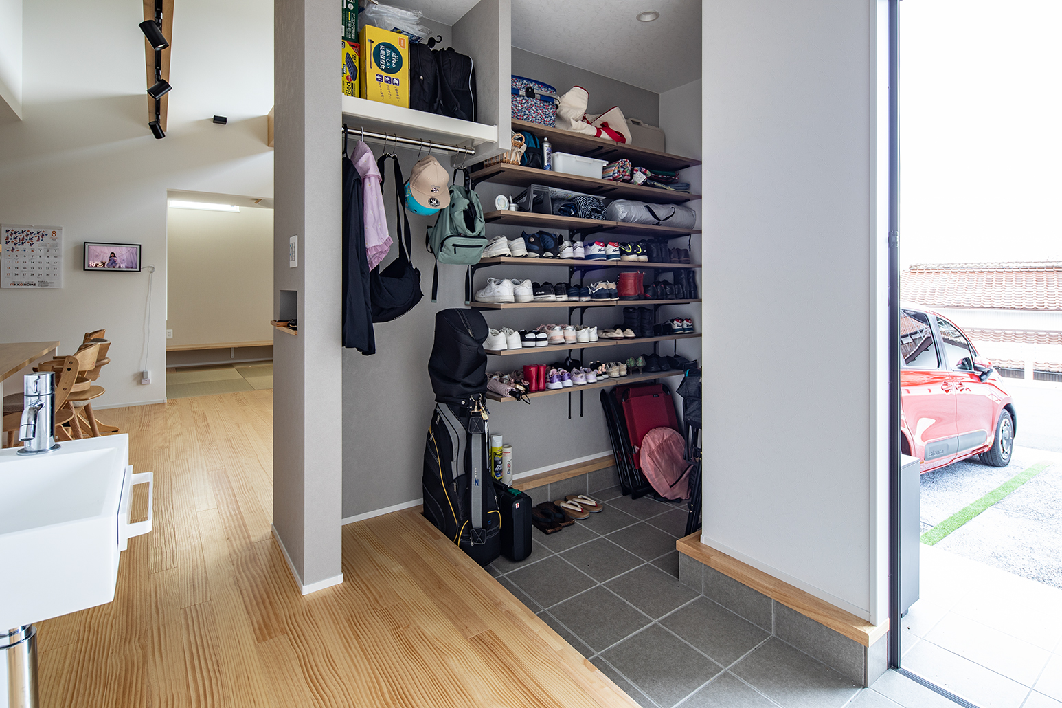 一度に複数人が使えるよう幅を広く取った三和土。シューズクローゼットは靴やベビーカーだけでなく上着をかける場所も設けている。