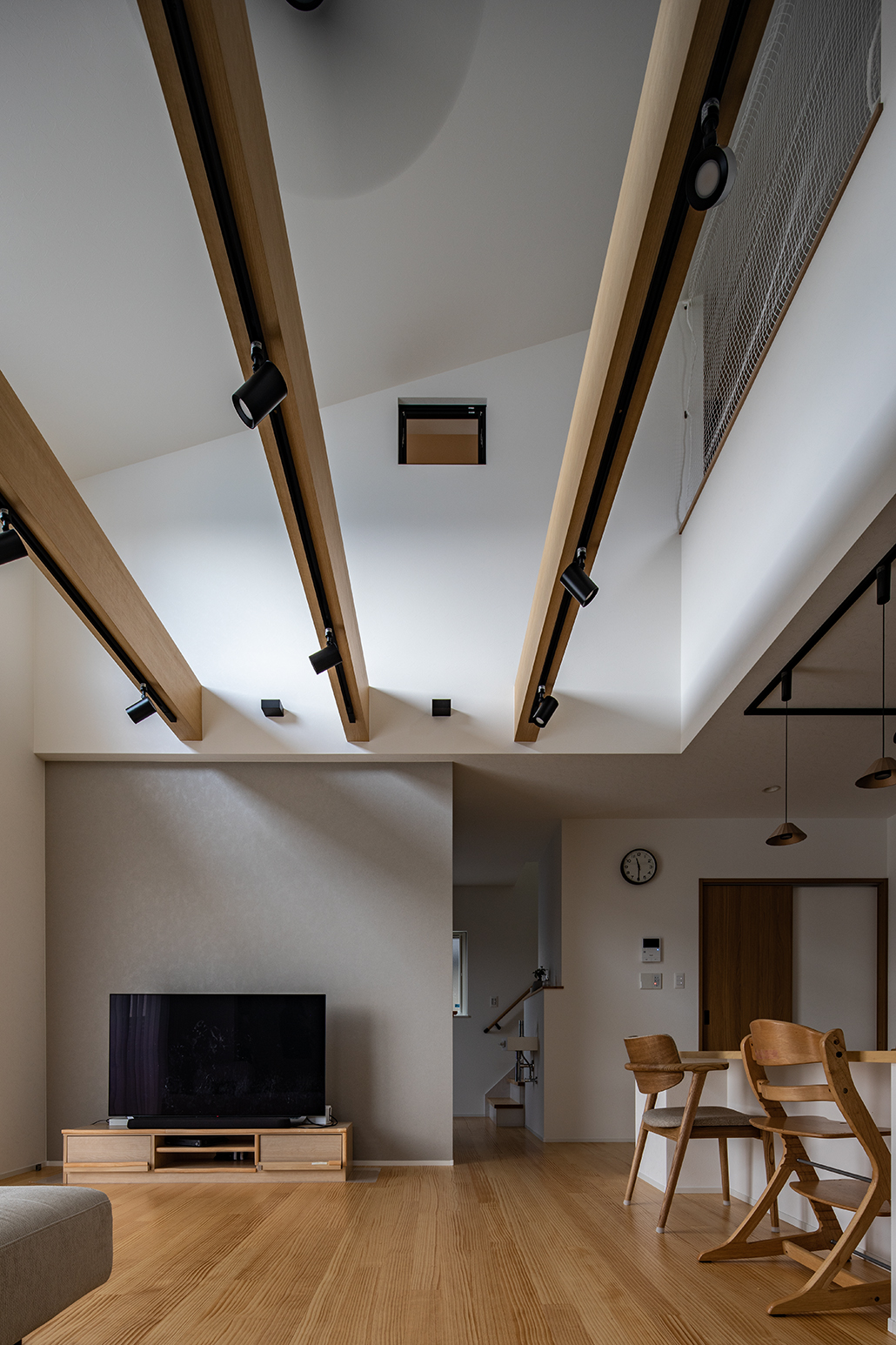 吹き抜けの勾配天井によって開放的なリビング。住まいを支える大きな梁は見た目もダイナミック。