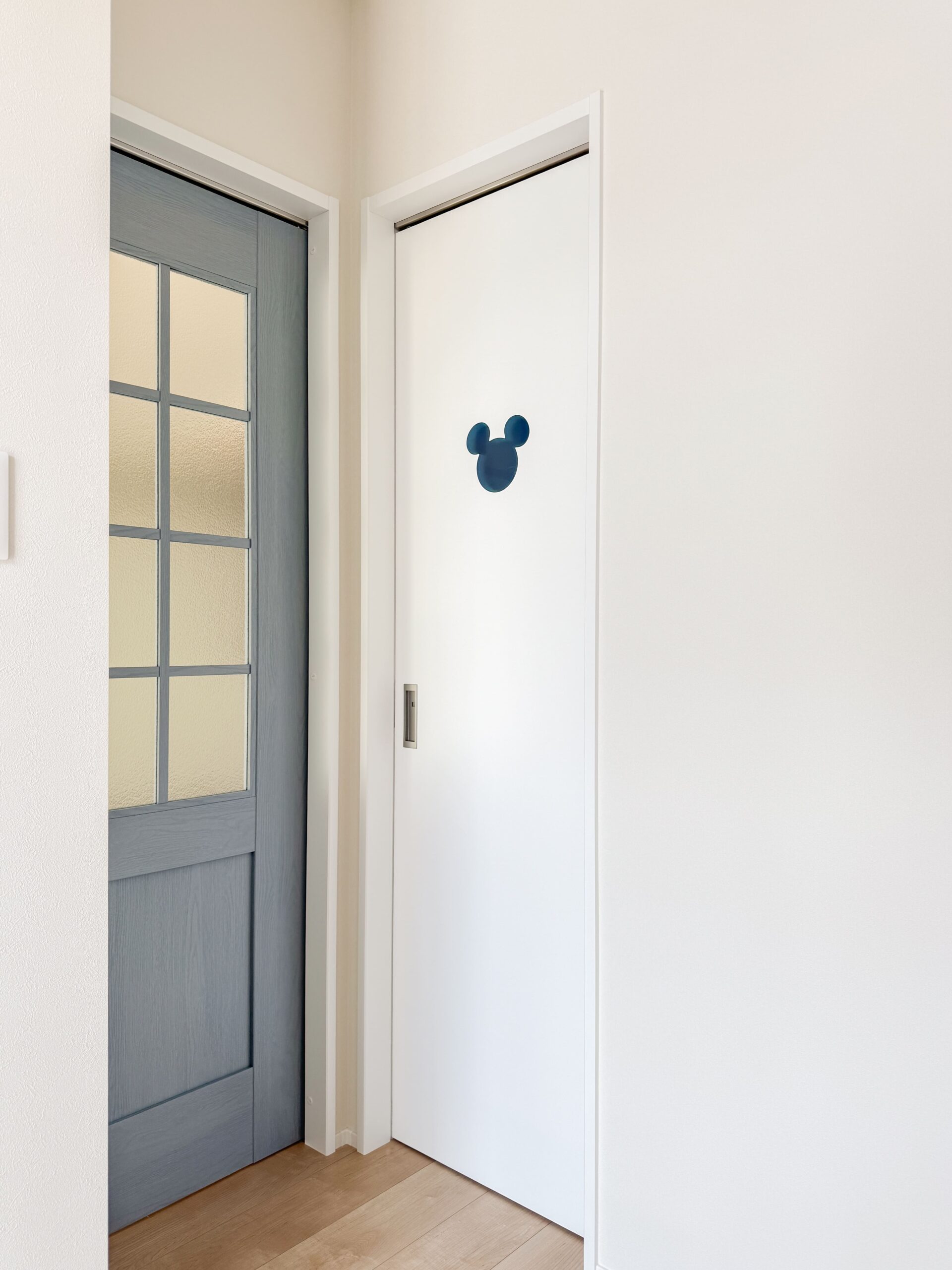 トイレのドアにはキャラクターモチーフをあしらい、暮らしに遊び心をプラス。LDKのドアはかわいいブルーグレーオーク柄。ガラスがアクセント。北欧風のかわいらしい雰囲気に。