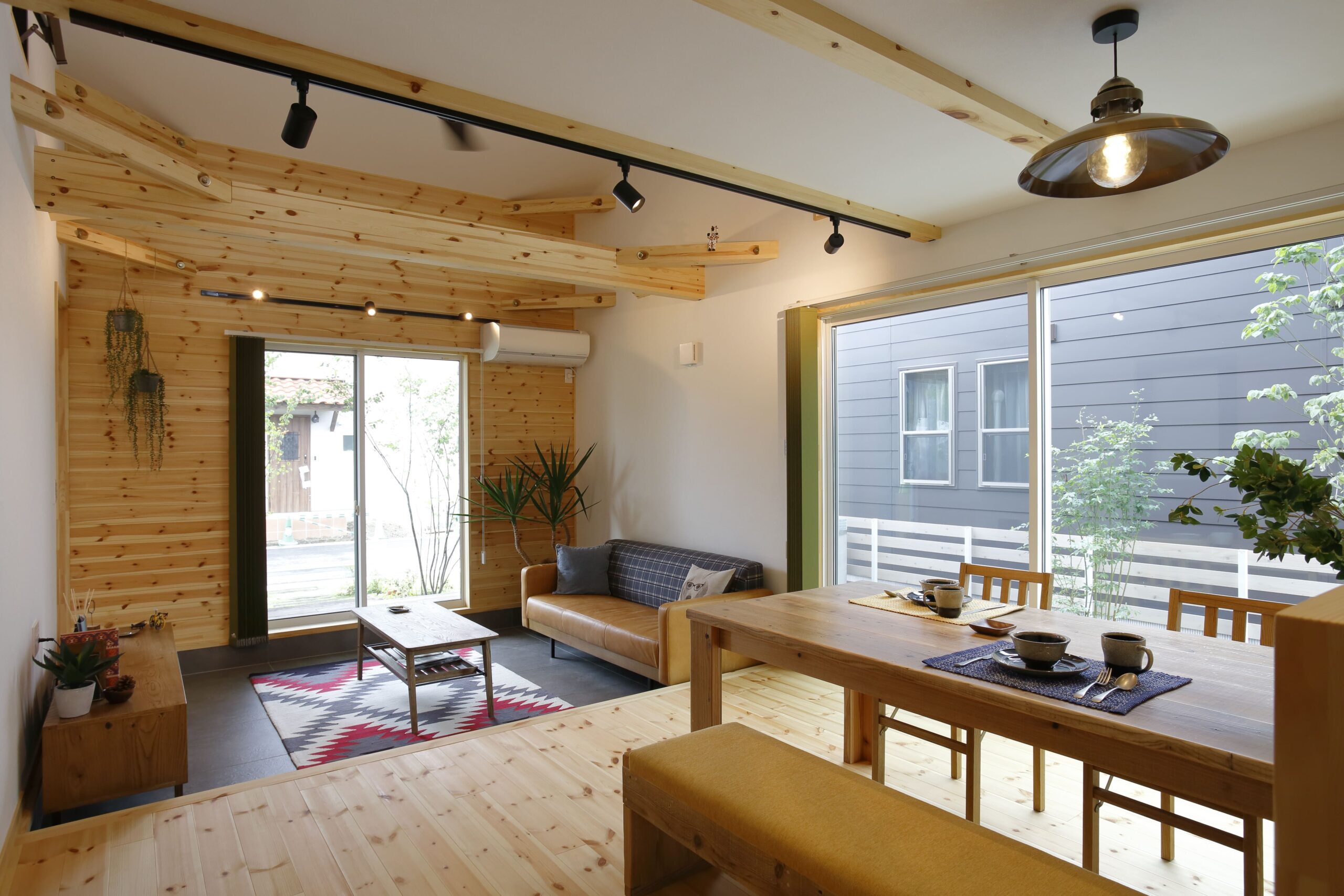 大きな窓から光が差し込む土間リビングとダイニング。木の温もりに包まれながら、家族が自然と集まり会話が弾む心地よい空間です。