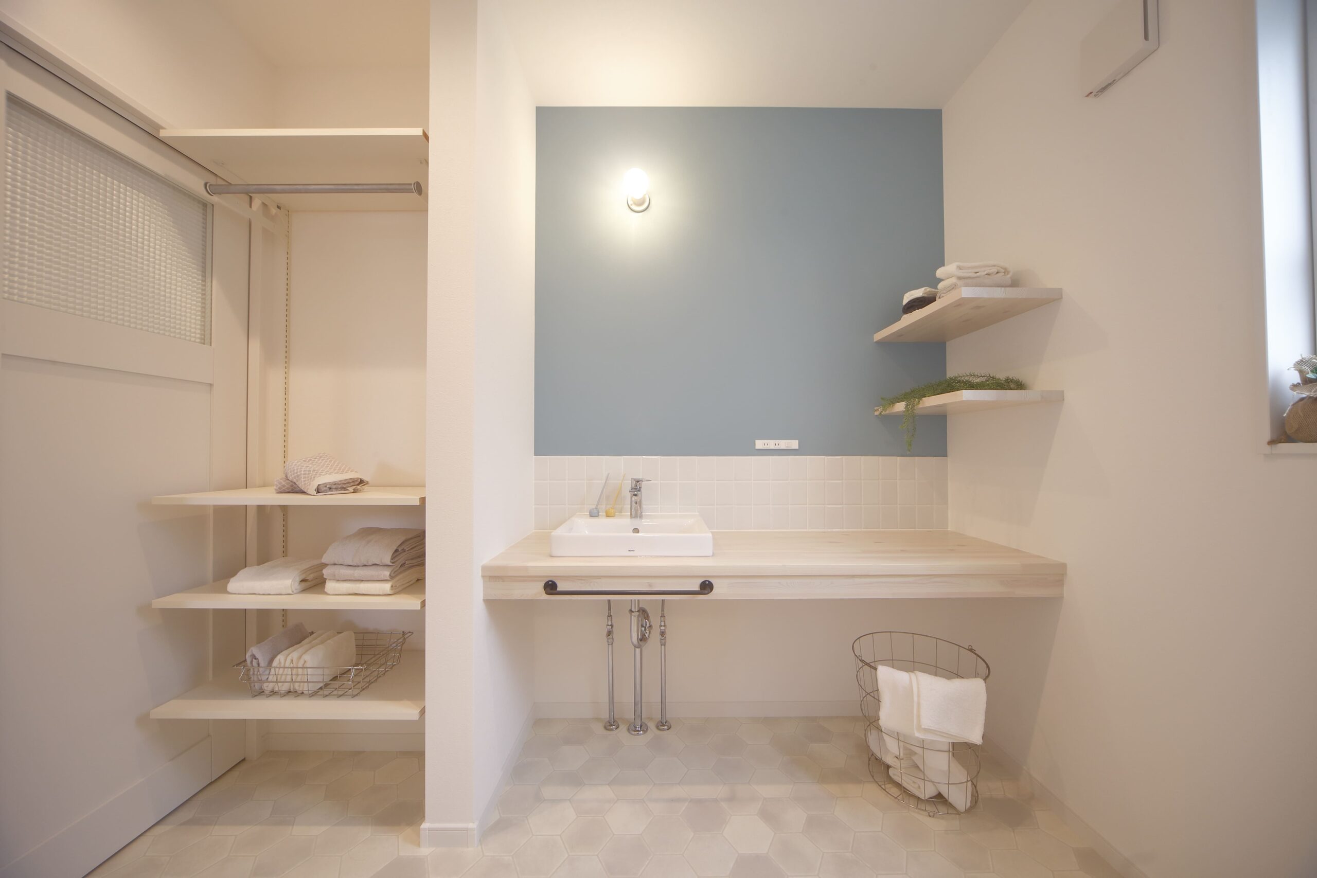 アクセントクロスのブルーが爽やかな洗面スペース。オープン棚と広々カウンターで使いやすさも抜群。