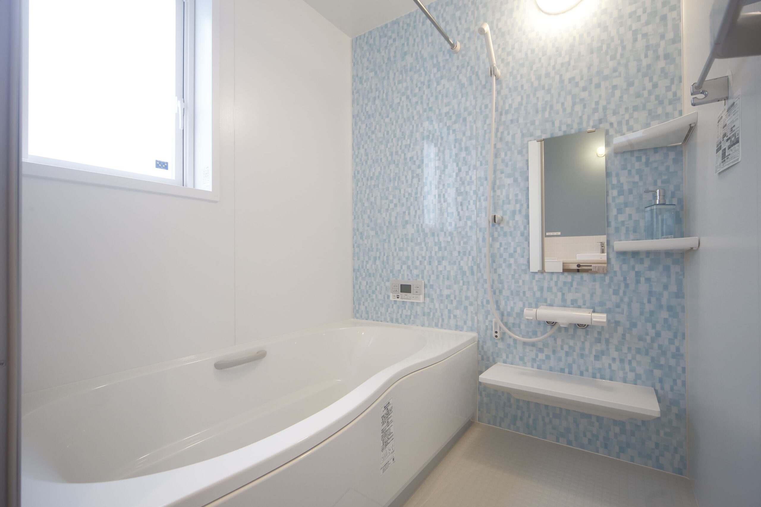 ブルーのモザイク調パネルが印象的なバスルーム。明るく開放感のある空間で、リラックスタイムを演出します。