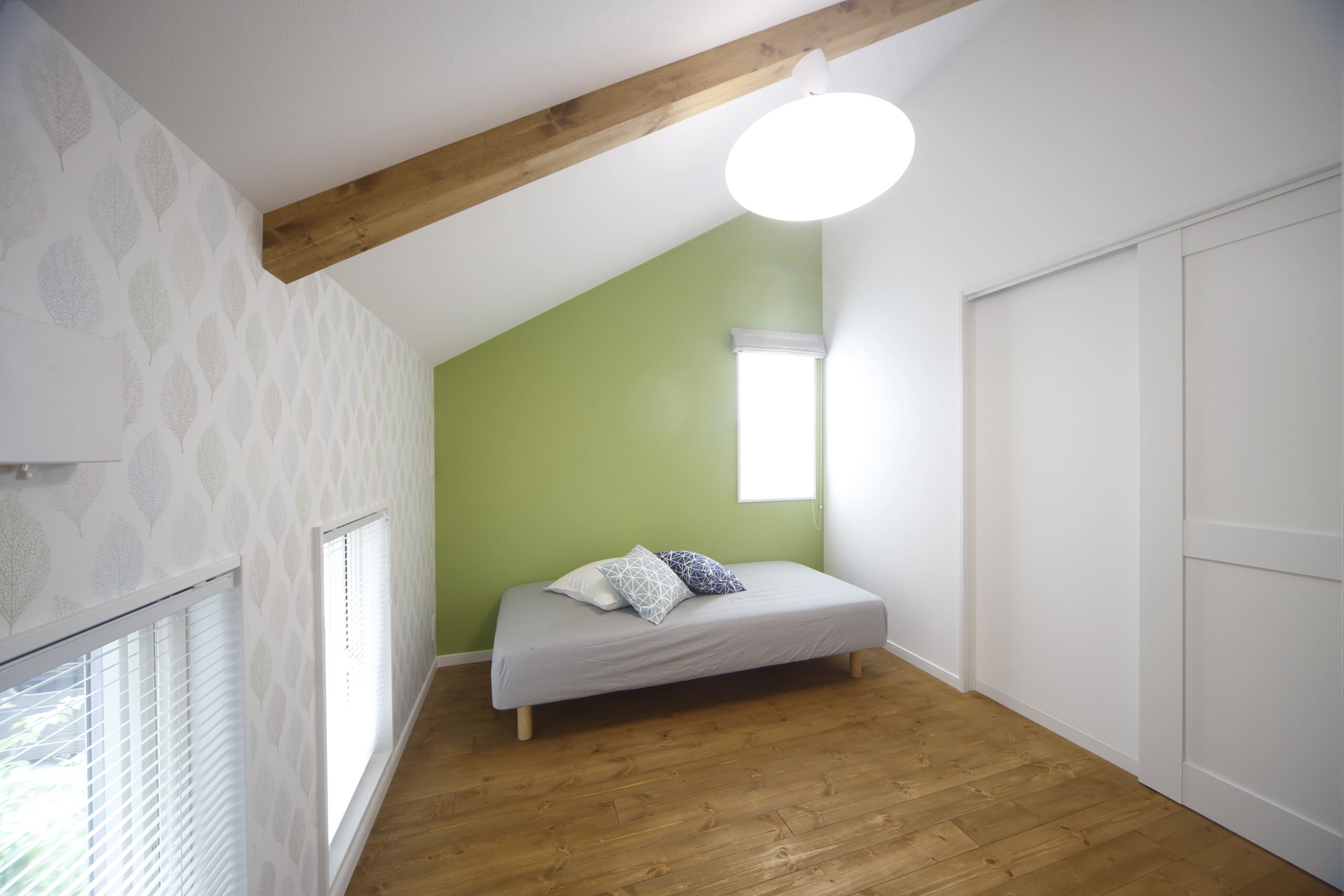 勾配天井を活かした寝室は、北欧テイストのアクセントクロスが映えるシンプルでやさしい空間。スキップフロアの高低差が生むプライベート感も魅力です。