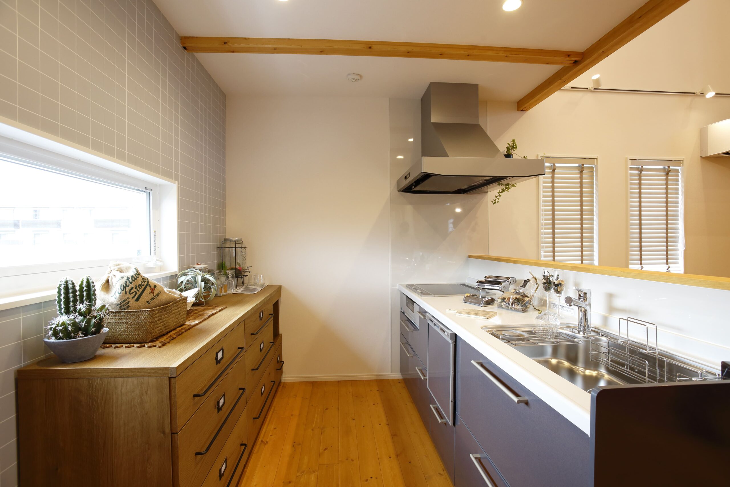 木の温もりとグレーのクロスが調和する、収納力も魅力のキッチン。