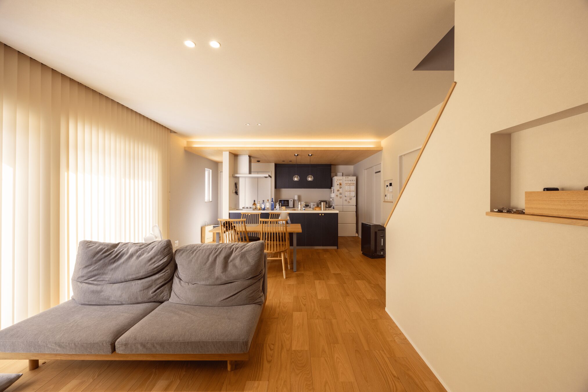 深いネイビーのキッチンと木目天井が調和し、落ち着いたリビングダイニングに。間接照明がやわらかな雰囲気を演出し、ご夫婦の趣味であるゲームや動画を楽しむ時間をより豊かにしてくれます。