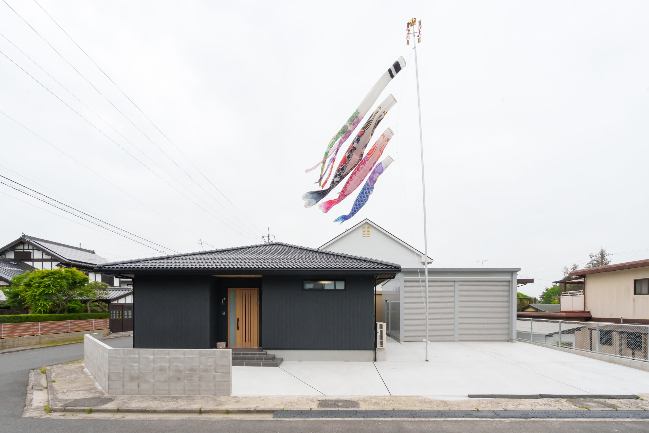 ご主人が好む瓦葺きの寄棟屋根とチャコールグレーの外壁が目を惹く外観。玄関ドアのスリット窓からは玄関内に明るさが採りこめる。