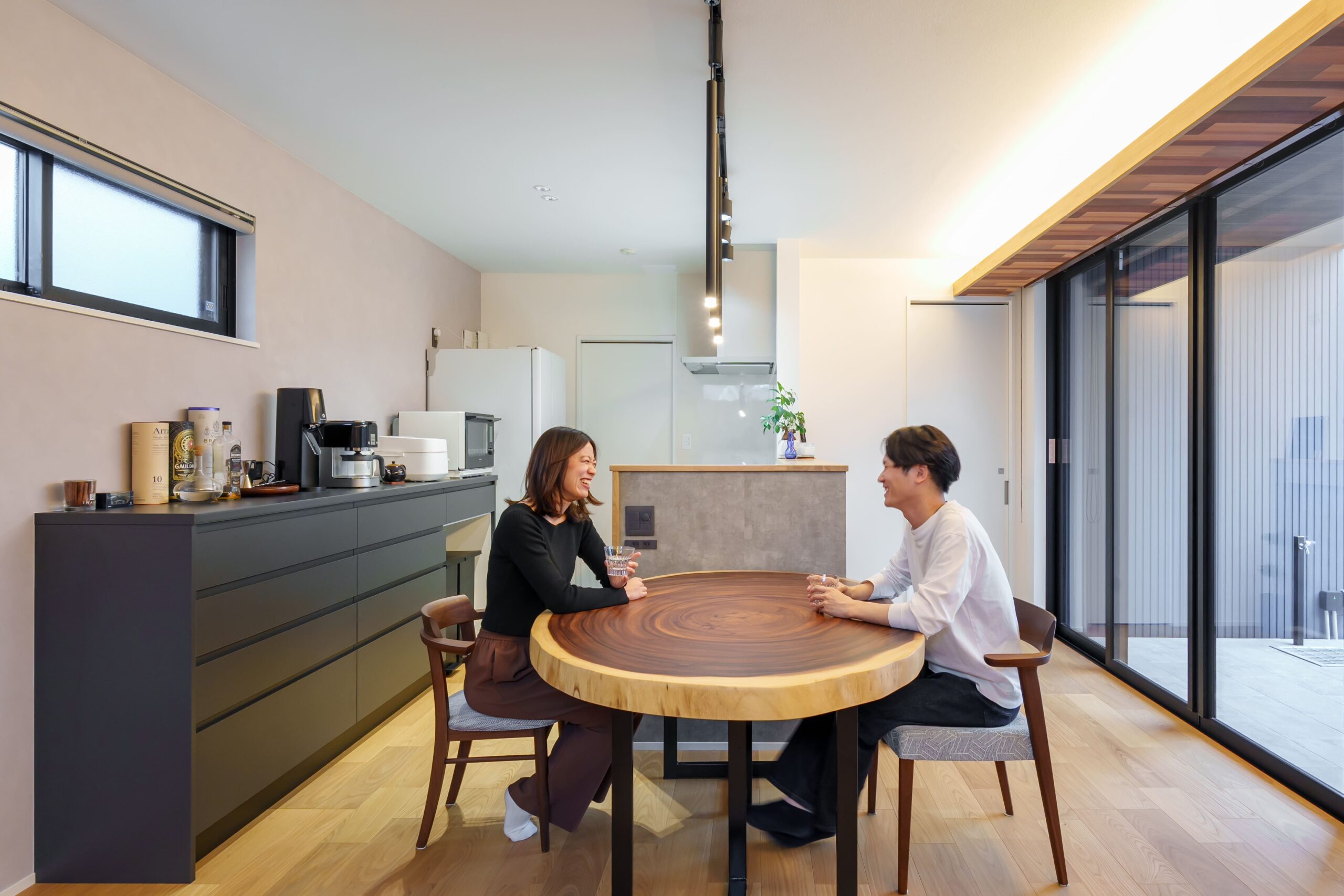 モンキーポッドの一枚板テーブルが映えるダイニング空間。後ろのカップボードはマットな質感の黒に惹かれて選択。