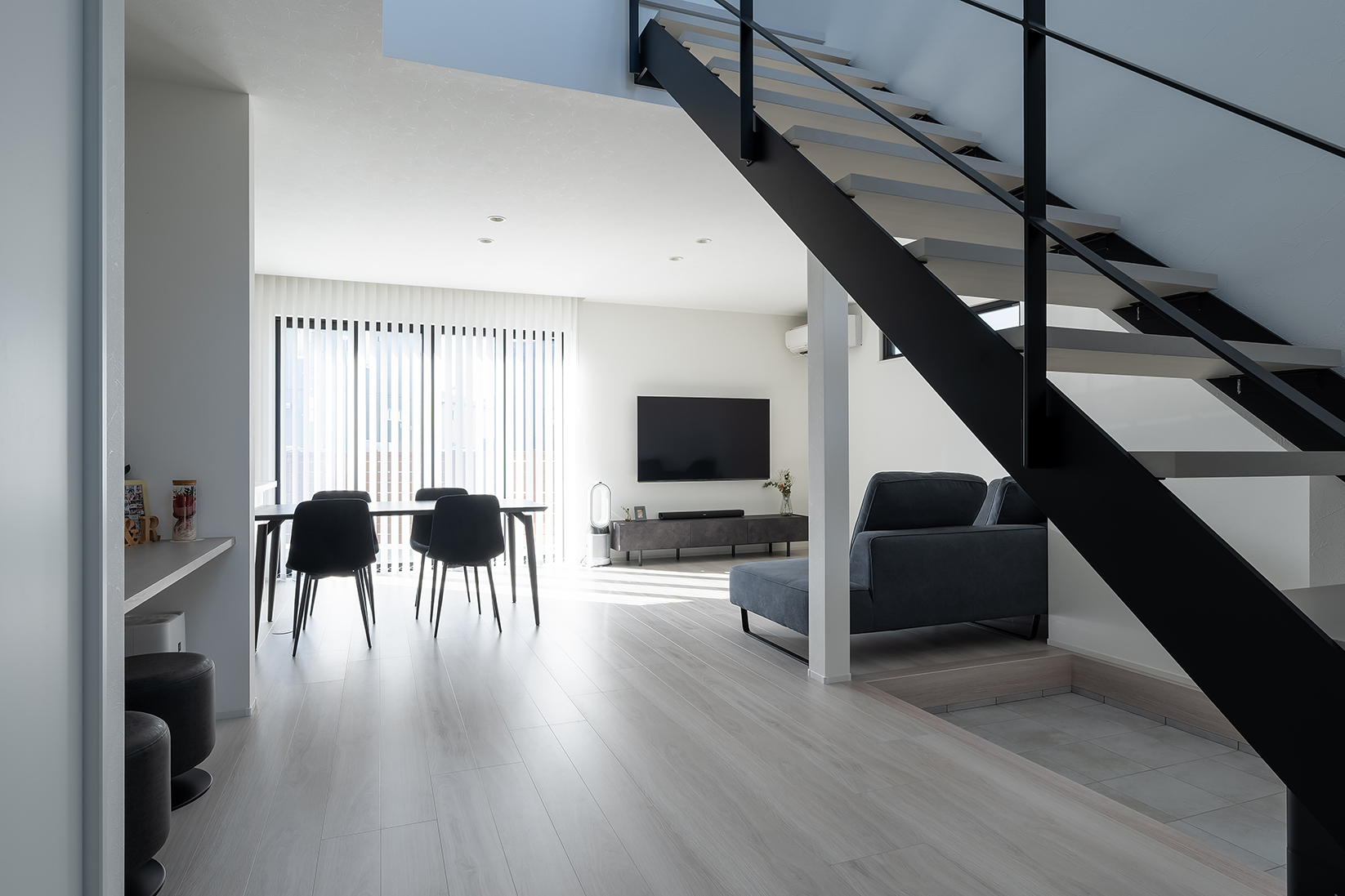 明るく開放的な吹き抜けに、アイアンを配した視界を遮らないスケルトン階段で、さらなる開放感をもたらすLD空間が広がる。庭につながる窓はバーチカルブラインドでスタイリッシュに。プライバシーを確保しつつ採光をコントロールできる。キッチン横にはお子さんが宿題をしたりPC作業などができるカウンターを設けた。