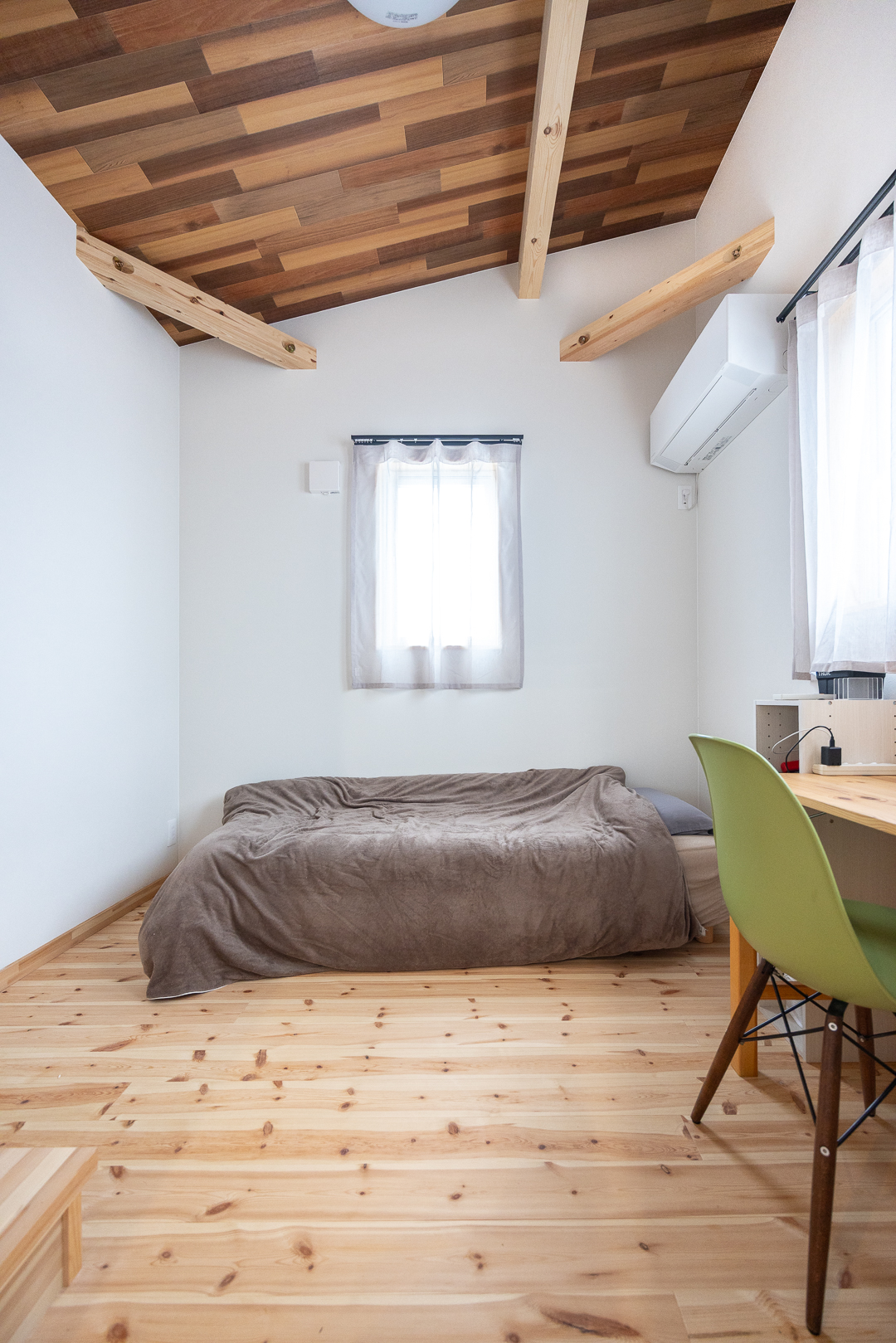 勾配天井の開放感あふれる洋室。高い天井と木目の質感が、空間にあたたかみとゆとりをもたらす。ゆったりと自分時間を過ごせる一部屋。