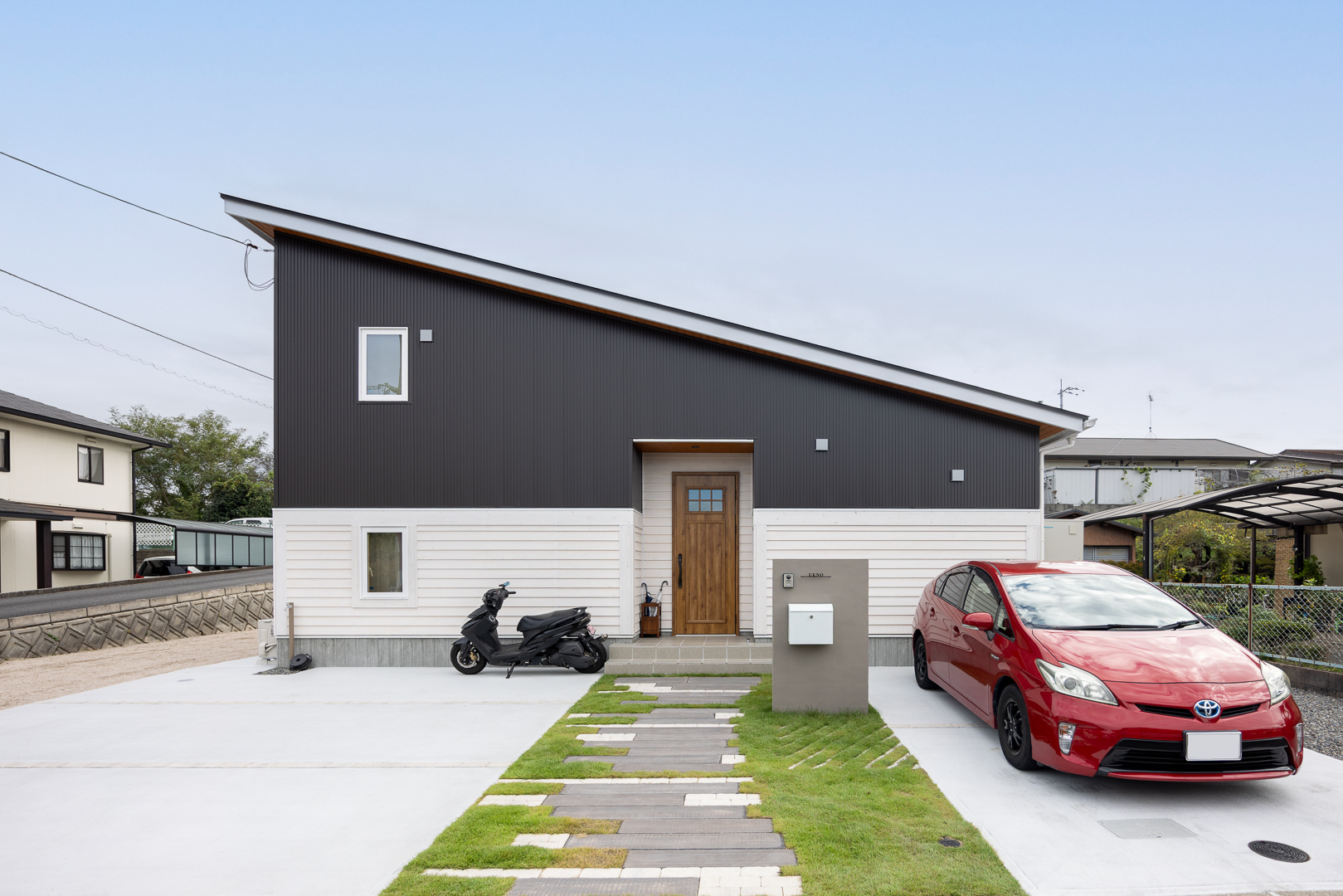 片流れ屋根とツートン外壁が印象的な外観。ガルバリウムと板張りの組み合わせが、シンプルながらも個性を感じさせる。玄関まで続くアプローチは、家に帰るたびに心が弾むデザインに。