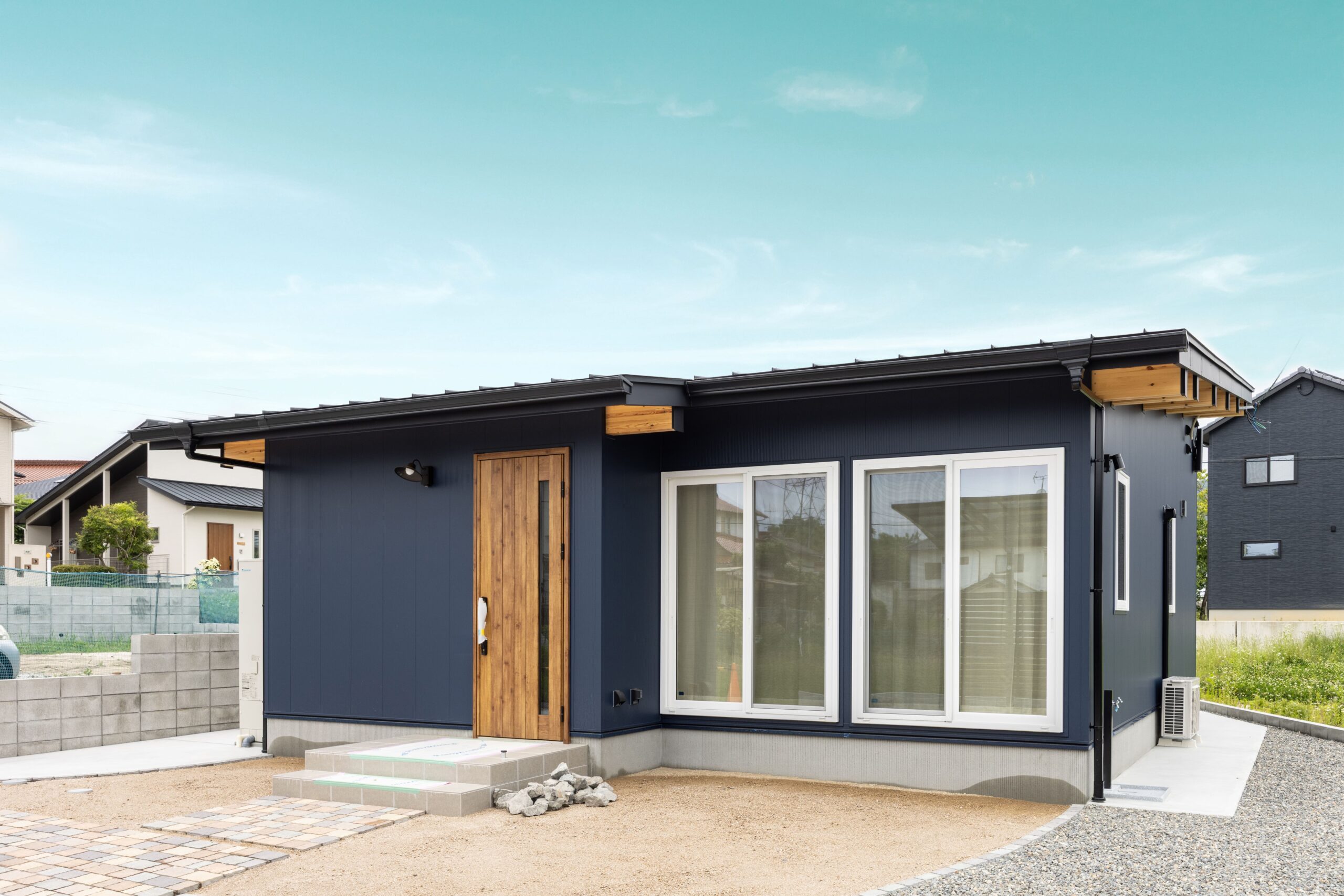 深みのあるネイビーの外壁に、木の素材感が映える外観。